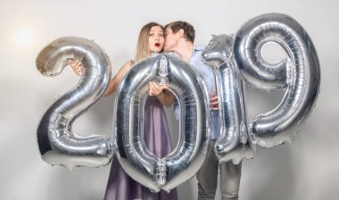 Yeni 2019 yılı önümüzdeki kavramı - neşeli genç adam ve kadın gümüş renkli numaraları tutuyorsun