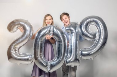 Yeni 2019 yılı önümüzdeki kavramı - neşeli genç adam ve kadın gümüş renkli numaraları tutuyorsun