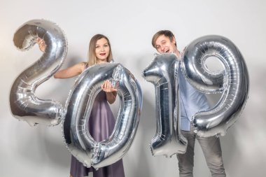Yeni 2019 yılı önümüzdeki kavramı - neşeli genç adam ve kadın gümüş renkli numaraları tutuyorsun