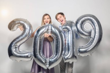 Yeni 2019 yılı önümüzdeki kavramı - mutlu genç adam ve kadın beyaz arka plan üzerinde gümüş renkli numaraları tutuyorsun