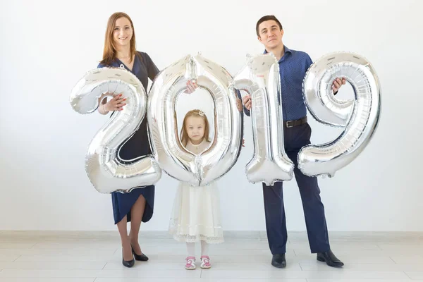 Nuevo 2019 Año viene concepto - Alegre madre, padre e hija están sosteniendo números de color plata en el interior . — Foto de Stock