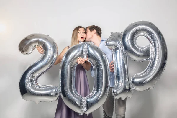 Ano Novo, celebração e feriados conceito - engraçado amor casal segurando sinal 2019 feito de balões de prata para o ano novo no fundo branco — Fotografia de Stock