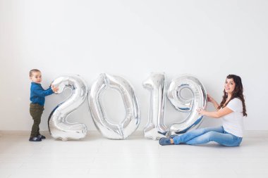 Yeni 2019 yılı konsept - neşeli anne ve küçük oğlu gümüş renkli numaralarla kapalı geliyor.