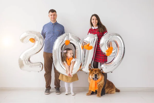 Nuevo 2019 Año viene concepto - Familia feliz con perro están sosteniendo números de color plata en el interior . — Foto de Stock