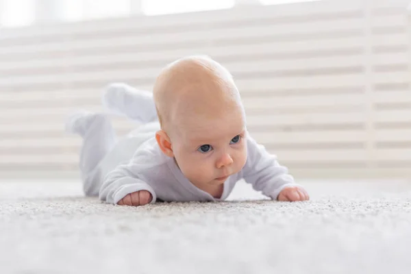 Childhood, babyhood and people concept - little baby boy or girl crawling on floor at home — Stock Photo, Image