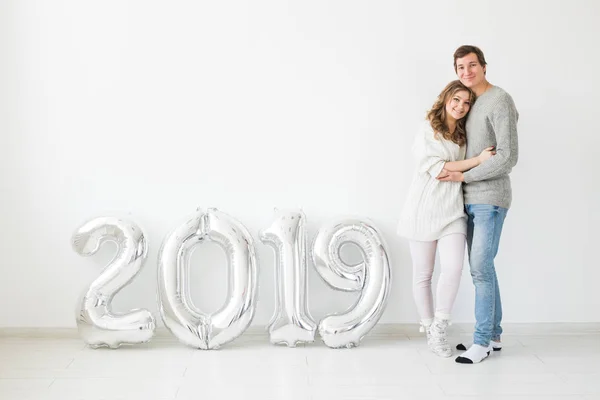Nuevo 2019 Año viene concepto - Feliz joven hombre y mujer con números de color plata sobre fondo blanco — Foto de Stock
