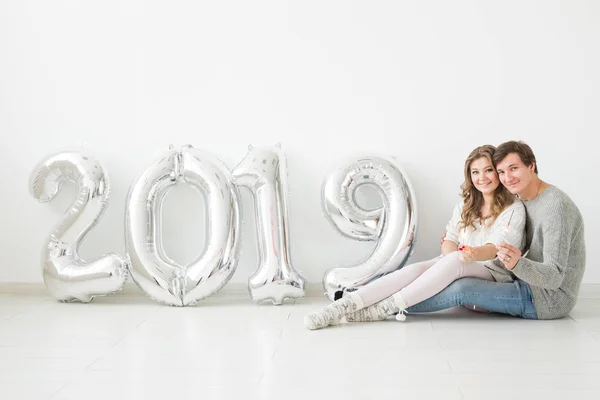 Año nuevo, celebración y concepto de vacaciones - pareja de amor con signo 2019 hecho de globos de plata para el año nuevo sobre fondo blanco — Foto de Stock