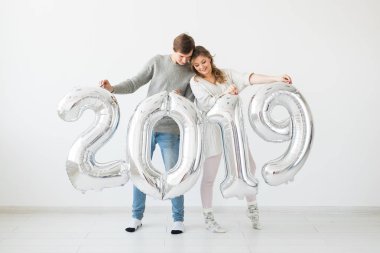 Yeni 2019 yılı önümüzdeki kavramı - mutlu genç adam ve kadın beyaz arka plan üzerinde gümüş renkli numaraları tutuyorsun