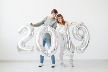 Yeni 2019 yılı önümüzdeki kavramı - komik genç adam ve kadın beyaz arka plan üzerinde gümüş renkli numaraları tutuyorsun