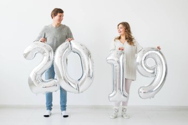 Yeni yıl, kutlama ve tatil kavramı - komik aşk çift holding yeni yıl için gümüş balon beyaz zemin üzerine yapılan 2019 imzalamak