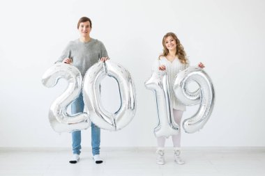 Yeni 2019 yılı önümüzdeki kavramı - neşeli genç adam ve kadın gümüş renkli numaraları tutuyorsun