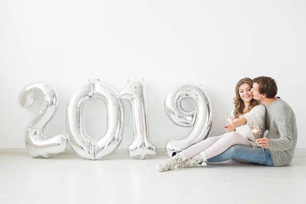 Año nuevo, celebración y concepto de vacaciones - pareja de amor con signo 2019 hecho de globos de plata para el año nuevo sobre fondo blanco — Foto de Stock