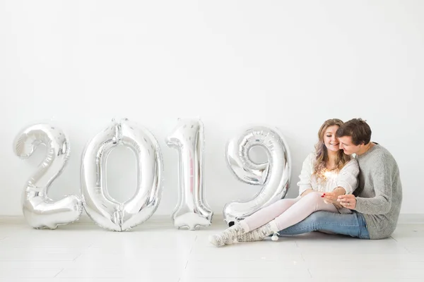 Νέο έτος 2019 έρχεται έννοια - ρομαντικό νεαρός άνδρας και γυναίκα με ασημένια χρωματισμένα αριθμοί σε λευκό φόντο — Φωτογραφία Αρχείου