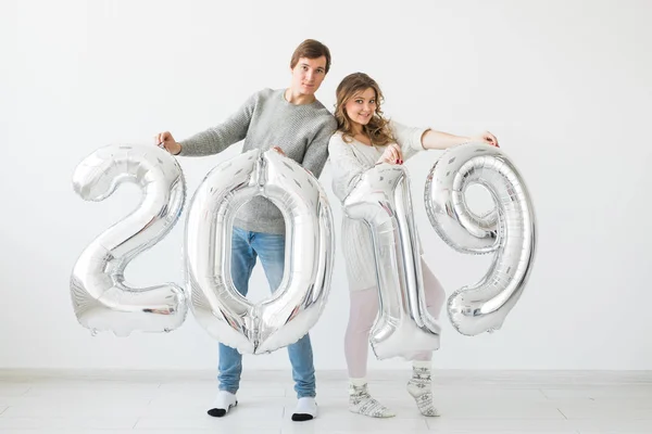 Novo 2019 Ano está chegando conceito - Jovem alegre e mulher estão segurando números coloridos de prata — Fotografia de Stock