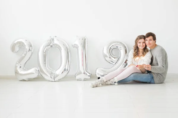 Año nuevo, celebración y concepto de vacaciones - pareja de amor con signo 2019 hecho de globos de plata para el año nuevo sobre fondo blanco — Foto de Stock