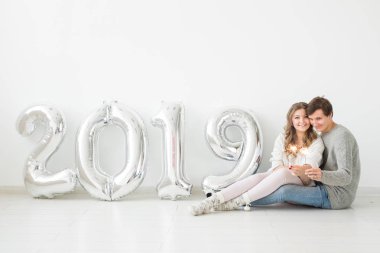 Yeni 2019 yılı konsept - mutlu genç adam ve kadın beyaz arka plan üzerinde gümüş renkli numaralarla geliyor