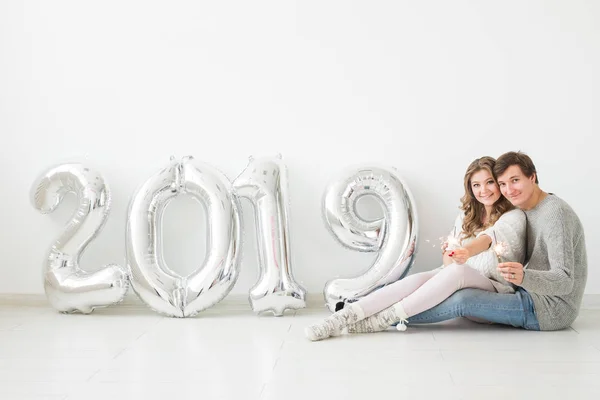 Nuevo 2019 Año viene concepto - Feliz joven hombre y mujer con números de color plata sobre fondo blanco — Foto de Stock