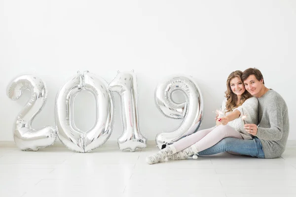 Nuevo 2019 Año viene concepto - Romántico joven hombre y mujer con números de color plata sobre fondo blanco — Foto de Stock