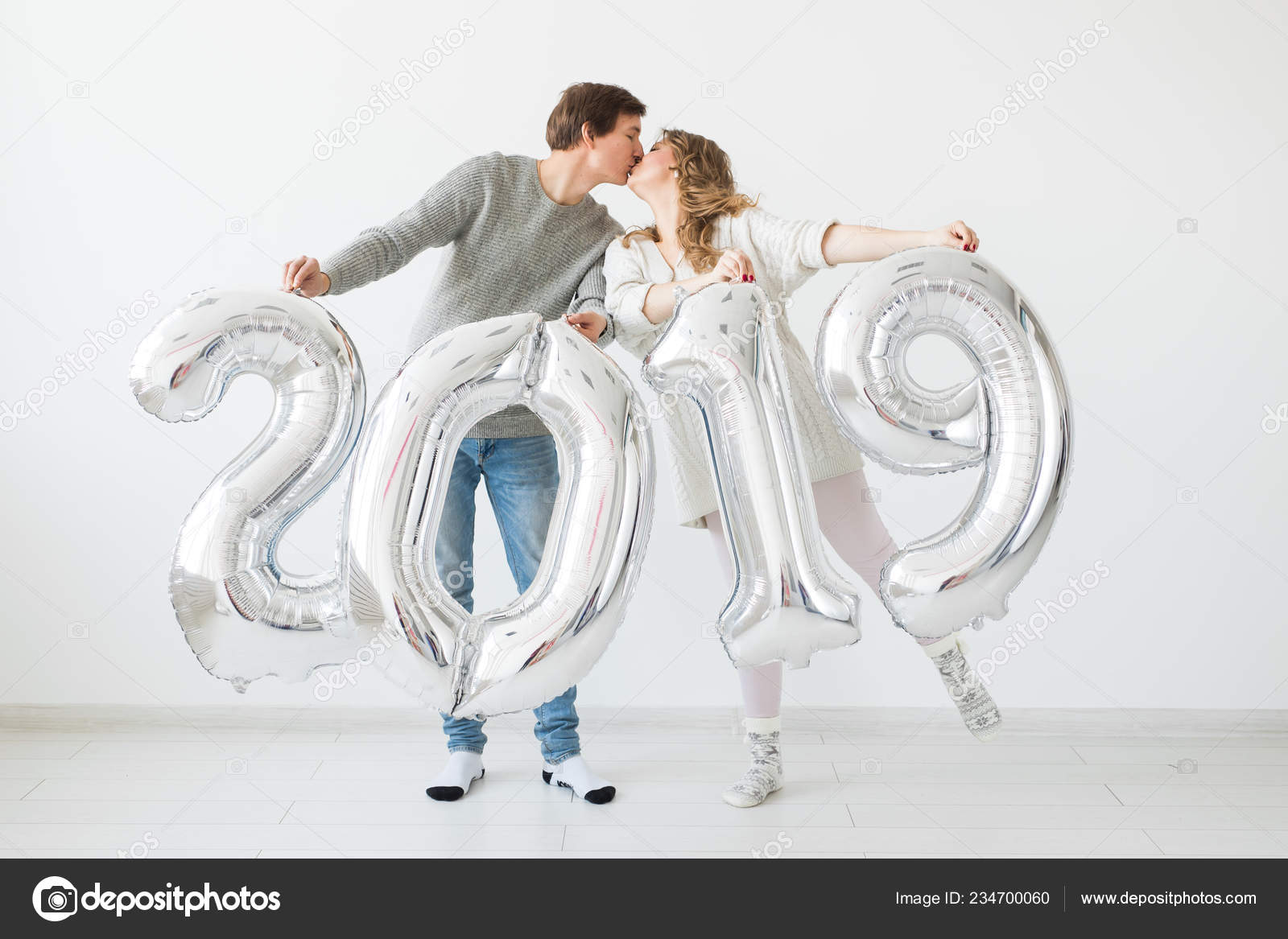 Año nuevo, celebración y concepto de días festivos - divertida pareja de  amor sosteniendo el cartel 2019 hecho de globos de plata para el año nuevo  sobre fondo blanco: fotografía de stock ©