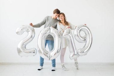 Yeni 2019 yılı önümüzdeki kavramı - komik genç adam ve kadın beyaz arka plan üzerinde gümüş renkli numaraları tutuyorsun