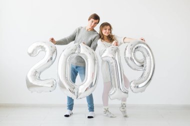 Yeni 2019 yılı önümüzdeki kavramı - mutlu genç adam ve kadın beyaz arka plan üzerinde gümüş renkli numaraları tutuyorsun