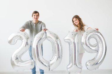 Yeni 2019 yılı önümüzdeki kavramı - neşeli genç adam ve kadın gümüş renkli numaraları tutuyorsun