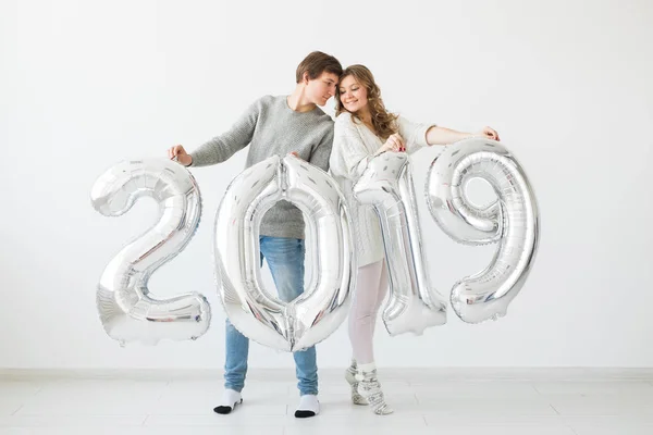 Νέο έτος 2019 είναι προσεχείς έννοια - χαρούμενος νεαρός άνδρας και γυναίκα κρατάτε ασημένια χρωματισμένα αριθμοί σε λευκό φόντο — Φωτογραφία Αρχείου