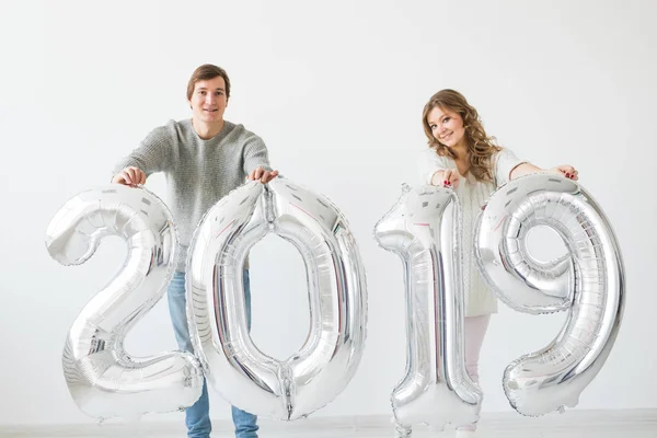 Nuevo 2019 Año viene concepto - Alegre joven hombre y mujer están sosteniendo números de color plata — Foto de Stock