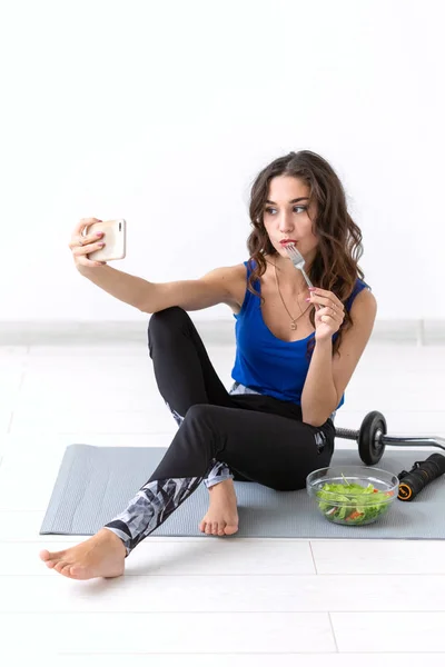 Mode de vie sain, concept de personnes - jeune femme manger une salade après le sport et faire du selfie — Photo