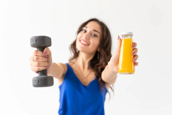 Sport, stile di vita sano, concetto di persone - giovane donna con un manubrio in mano e una bottiglia di succo in un'altra mano — Foto Stock