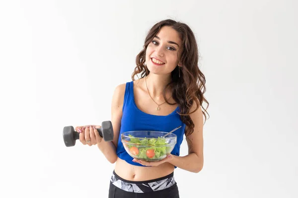 Esporte, estilo de vida são, conceito de pessoas - mulher morena jovem com salada e um halteres. Ela está sorrindo e desfrutando do estilo de vida saudável — Fotografia de Stock