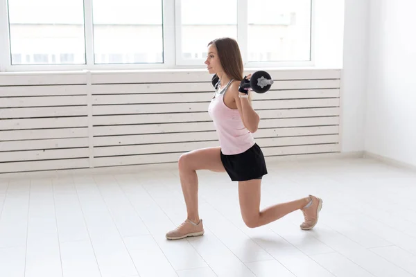 Fitness, deporte, concepto de personas - mujer joven en traje deportivo, guantes está en cuclillas con bar — Foto de Stock