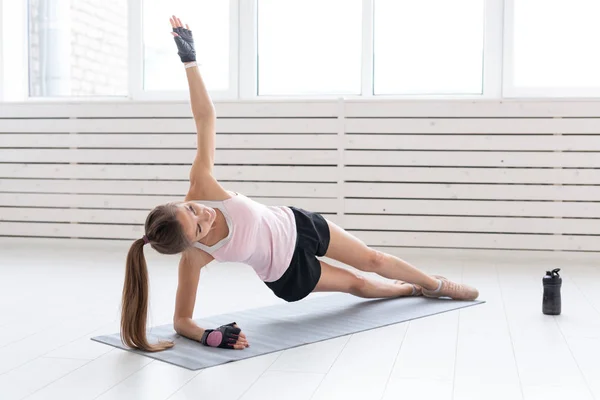 Concepto de deporte, yoga y personas: la mujer joven está haciendo ejercicio. Ella está presionando en el suelo en el gimnasio — Foto de Stock