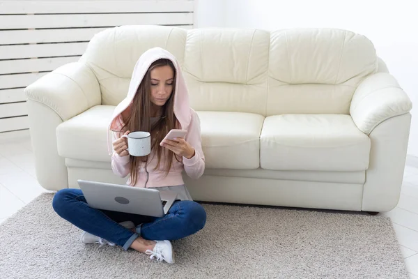 Technologies, freelance et concept de personnes - jeune femme travaillant à la maison, elle boit du thé sur le sol, bavarde en mobile — Photo