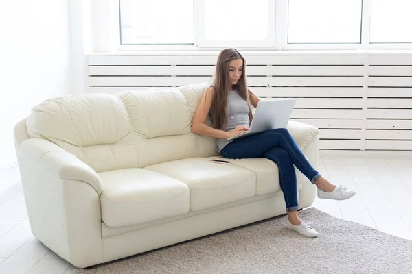 Koncepcja technologii, freelance i ludzie - młoda kobieta siedzi na białej kanapie i rozmowy w netbook — Zdjęcie stockowe