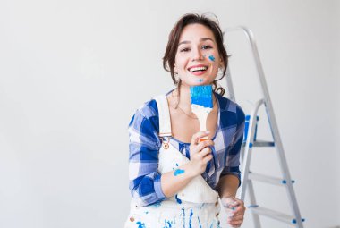 Tadilat, yenileme ve insanlar kavramı - genç kadın duvar boyama ve çok mutlu gibi görünüyor o renkli yanak ile