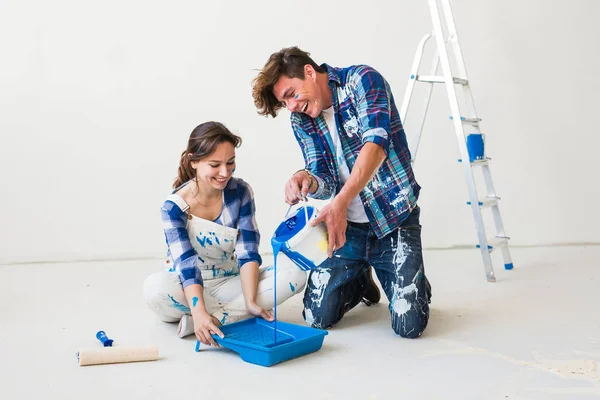Concept de rénovation, de redécoration et d'intérieurs - Jeune couple assis sur le sol blanc et versez de la peinture — Photo