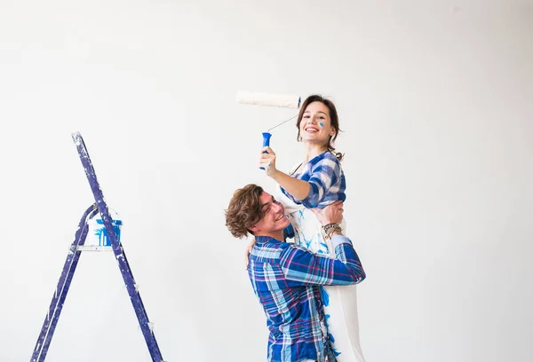 Renovación, redecoración y concepto familiar: el joven sostiene a la joven en sus brazos durante la renovación en el apartamento — Foto de Stock