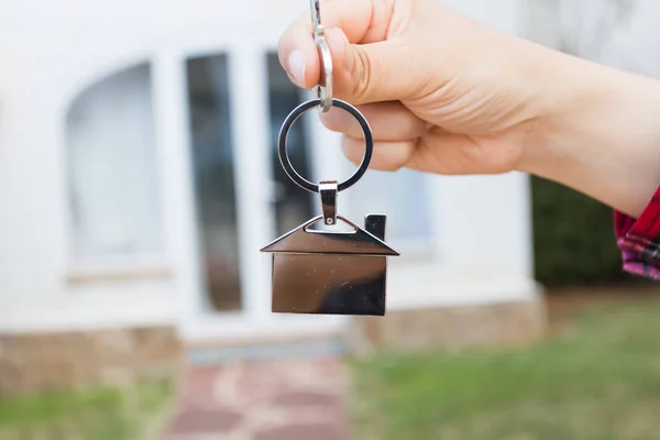 Tecla de mano con llavero en forma de casa. Llave de la casa en el fondo de nuevo hogar —  Fotos de Stock