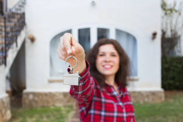 Concepto de bienes raíces y propiedad - Mujer joven y feliz frente a un nuevo hogar con nuevas llaves de la casa —  Fotos de Stock