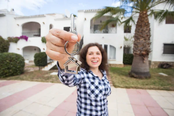 Nueva casa, casa, propiedad e inquilino - Joven mujer divertida sosteniendo la llave en frente de su nueva casa después de comprar bienes raíces —  Fotos de Stock