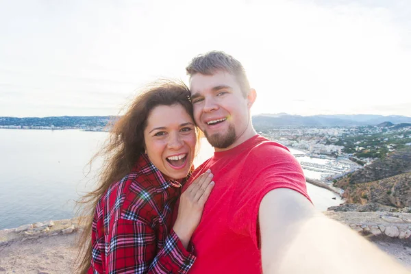 Viagens, turismo e conceito de férias - Casal feliz levando selfie perto de um mar — Fotografia de Stock