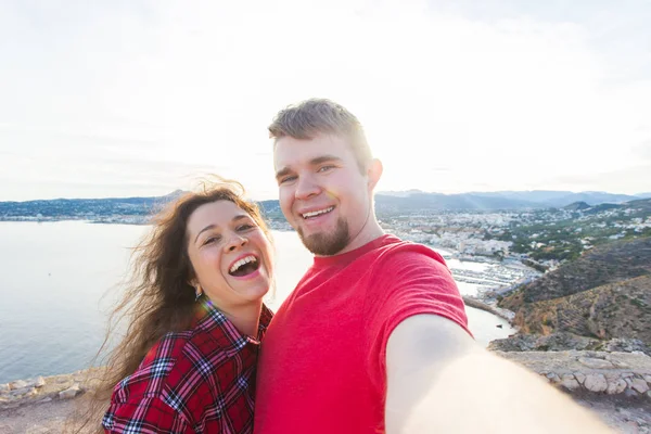 Viajes, vacaciones y concepto de vacaciones - Pareja joven tomando selfie juntos en una costa — Foto de Stock