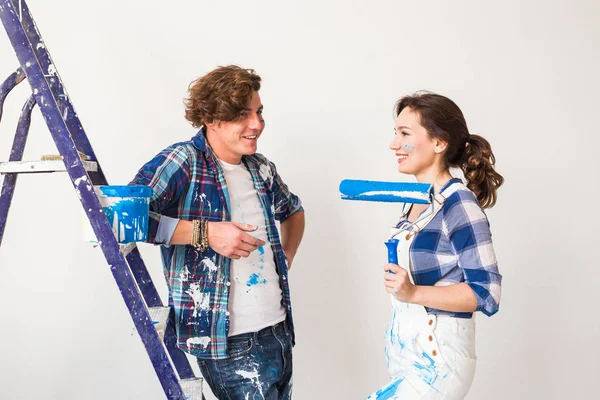 Reparación, renovación y amor concepto de pareja - familia joven haciendo reparación y pintura de paredes juntos y riendo — Foto de Stock