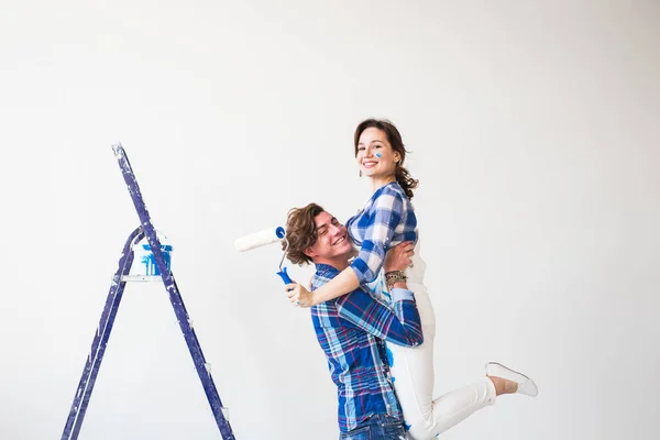 Renovering, ommöblering och familjen koncept - ung man håller ung kvinna i famnen under renovering i lägenhet — Stockfoto