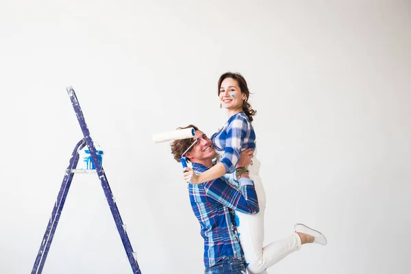 Renovación, redecoración y concepto familiar: el joven sostiene a la joven en sus brazos durante la renovación en el apartamento — Foto de Stock
