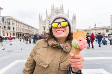 Tatiller, İtalya ve kış konsepti seyahat - genç komik kadın gezgin Milano Duomo Katedrali önünde dondurma dondurma ayakta tutan.