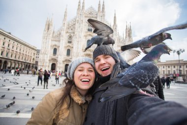 Milano Duomo Meydanı'nda güvercin ile kendi kendine portre çekici çift. Kış seyahat, İtalya ve ilişki kavramı