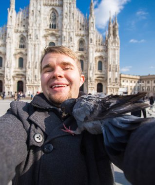 Kış seyahat, tatil ve kuşlar kavramı - yakışıklı erkek turist Milano'da ünlü Duomo Katedrali önünde selfie fotoğraf yapma komik güvercinler ile.