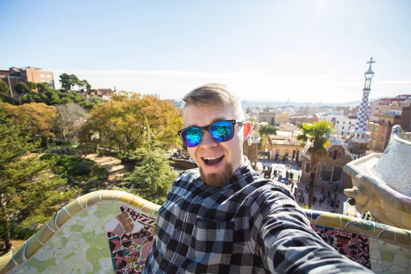 Concepto de viaje y vacaciones - Hombre feliz haciendo retrato selfie con smartphone en Park Guell, Barcelona, España . — Foto de Stock